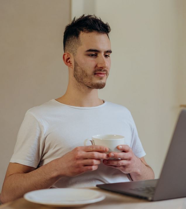 man-met-kopje-achter-laptop-VOG aanvragen zonder werkgever